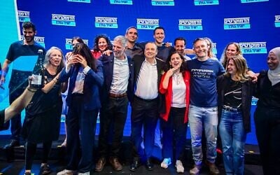 Les députés Naama Lazimi (veste rouge) et Gilad Kariv (à sa droite) célèbrent leur victoire avec d'autres responsables du parti Les Démocrates après avoir décroché respectivement les deuxième et troisième places sur la liste du parti pour la Knesset, derrière le chef du parti Yair Golan (à la droite de Kariv). Les candidats se sont réunis à Tel Aviv le 20 juillet 2026, à l'issue des primaires du parti. (Crédit : Avshalom Sassoni/Flash90)