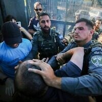 Le député Hadash, Ofer Cassif, se battant avec des agents de la police des frontières lors d'une cérémonie marquant le premier anniversaire de la mort du militant palestinien Awdah Hathaleen, dans le village d'Umm al-Khair, en Cisjordanie, dans la région de Masafer Yatta, le 28 juillet 2026. (Crédit : Wisam Hashlamoun/FLASH90)