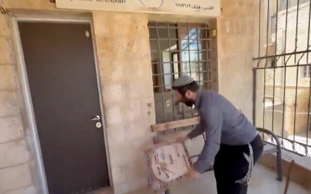 Zvi Sokot, député du parti HaTzionout HaDatit, se filmant en train de détruire l’enseigne d’une école palestinienne dans la Vieille Ville de Jérusalem, le 14 juillet 2026. (Crédit : Capture d’écran/X)