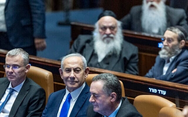 Le Premier ministre Benjamin Netanyahu (au centre), le ministre de la Justice Yariv Levin (à gauche) et le ministre de la Défense Israel Katz (à droite), avec derrière eux les députés ultra-orthodoxes Yitzchak Goldknopf, Moshe Gafni et Meïr Porush, à la Knesset peu avant le vote d’une loi interdisant les arrestations des réfractaires à la conscription ultra-orthodoxes et légitimant le non-enrôlement massif et continu des ultra-orthodoxes, le 14 juillet 2026. (Crédit : Chaïm Goldberg/Flash90)