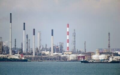 Illustration : un pétrolier (à droite) passe devant des raffineries de pétrole sur l'île de Bukom, au large de Singapour, le 17 mars 2022. (Crédit : Roslan Rahman/AFP)