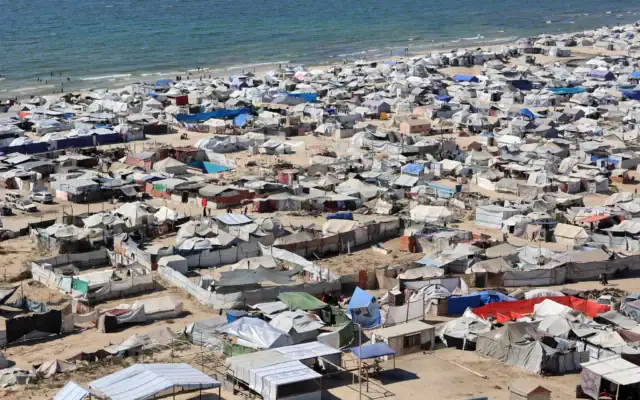 Photo d'illustration : des tentes et des abris destinés aux Palestiniens déplacés par le conflit sont installés dans un camp de fortune le long de la plage, près du port maritime situé à l’ouest de Gaza-City, le 19 juillet 2025. (Crédit : Omar AL-QATTAA / AFP)