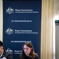 Des responsables se tiennent à l'entrée du lieu où siège la Commission royale sur l'antisémitisme et la cohésion sociale, à Sydney, le 25 mai 2026. (Crédit : David Gray/AFP)