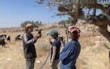 Des militants de l’organisation « Protective Presence » (à droite) faisant face à un résident d'implantation qui les filme également avec son téléphone portable, alors qu’il tente de pénétrer dans la maison d’une famille bédouine en Cisjordanie, à l’est de Ramallah, juste à la sortie du village de Taybeh, le 22 juin 2026. (Crédit : Ilia Yefimovich/AFP)