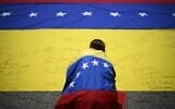 Illustration : Un militant syndicaliste, enveloppé dans un drapeau national vénézuélien, signant un autre drapeau national vénézuélien lors d'une manifestation, à Caracas, le 28 juillet 2026. (Crédit : Federico Parra/AFP)