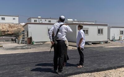 Des résidents d'implantations israéliens se tiennent devant des maisons après la réouverture de l'implantation de Ganim, en Cisjordanie, le 13 août 2026. (Crédit : Ilia Yefimovitch/AFP)