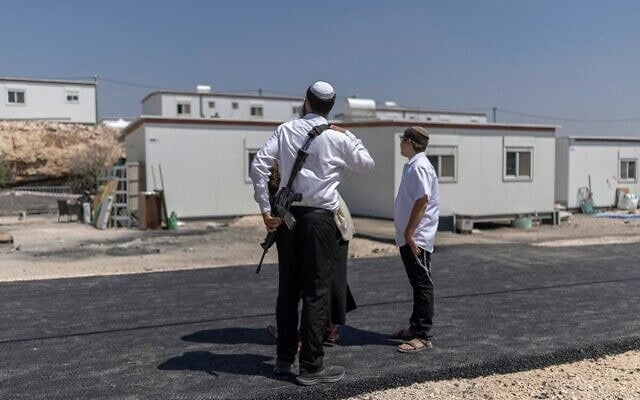 Des résidents d'implantations israéliens se tiennent devant des maisons après la réouverture de l'implantation de Ganim, en Cisjordanie, le 13 août 2026. (Crédit : Ilia Yefimovitch/AFP)