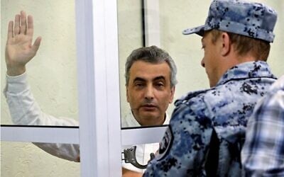 Un huissier passe les menottes à Lev Shlosberg, opposant politique russe condamné à 11 ans de prison pour avoir critiqué l'offensive de Moscou en Ukraine, dans un tribunal municipal de Pskov, dans le nord-ouest de la Russie, le 17 août 2026. (Crédit : Olga MALTSEVA/AFP)