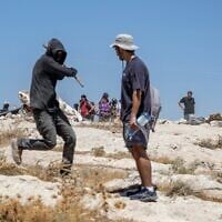 Un résident d'implantations israélien s'en prend à un militant de gauche dans un avant-poste israélien situé dans le village palestinien de Jannatah, au sud de la ville de Bethléem, le 25 août 2026. (Crédit : Ilia YEFIMOVICH/AFP)