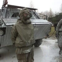 Des soldats de l'armée allemande à côté d'un char « Fuchs » de détection des menaces nucléaires, biologiques et chimiques, recouvert d'un liquide de décontamination après un exercice à la caserne du général Jaeger à Sonthofen, dans le sud de l'Allemagne, le 19 novembre 2001. (AP Photo/Diether Endlicher)