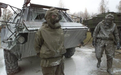 Des soldats de l'armée allemande à côté d'un char « Fuchs » de détection des menaces nucléaires, biologiques et chimiques, recouvert d'un liquide de décontamination après un exercice à la caserne du général Jaeger à Sonthofen, dans le sud de l'Allemagne, le 19 novembre 2001. (AP Photo/Diether Endlicher)