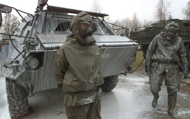 Des soldats de l'armée allemande à côté d'un char « Fuchs » de détection des menaces nucléaires, biologiques et chimiques, recouvert d'un liquide de décontamination après un exercice à la caserne du général Jaeger à Sonthofen, dans le sud de l'Allemagne, le 19 novembre 2001. (AP Photo/Diether Endlicher)