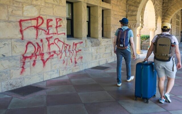 Des étudiants passant devant des graffitis près du bureau du président de l’université de Stanford, Richard Saller, à Palo Alto, en Californie, le 5 juin 2024. (Crédit : Nic Coury/AP)