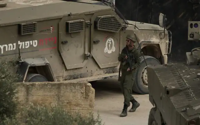 Un soldat de l'armée israélienne  marche, son arme à la main, dans une rue lors d'un raid militaire dans le village d'al-Yamun, en Cisjordanie, près de Jénine, le 17 février 2026. (Crédit: AP/Leo Correa)