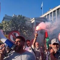 Un manifestant tenant une fusée éclairante tandis que d'autres scandent des slogans anti-Israël devant le ministère grec des Affaires étrangères, après l'interception par la marine israélienne d'une flottille d'activistes au large de Chypre, à Athènes, le 18 mai 2026. (Crédit : Petros Giannakouris/AP)