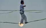 Une acrobate répète sur un fil tendu au-dessus de la vallée de Hinnom, à Jérusalem, avant sa performance aérienne à l'occasion de l'ouverture du Festival d'Israël, rappel de la traversée de cette vallée par Philippe Petit en 1987, le 27 juillet 2026. (AP Photo/Ohad Zwigenberg)