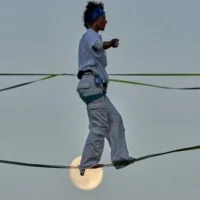 Une acrobate répète sur un fil tendu au-dessus de la vallée de Hinnom, à Jérusalem, avant sa performance aérienne à l'occasion de l'ouverture du Festival d'Israël, rappel de la traversée de cette vallée par Philippe Petit en 1987, le 27 juillet 2026. (AP Photo/Ohad Zwigenberg)