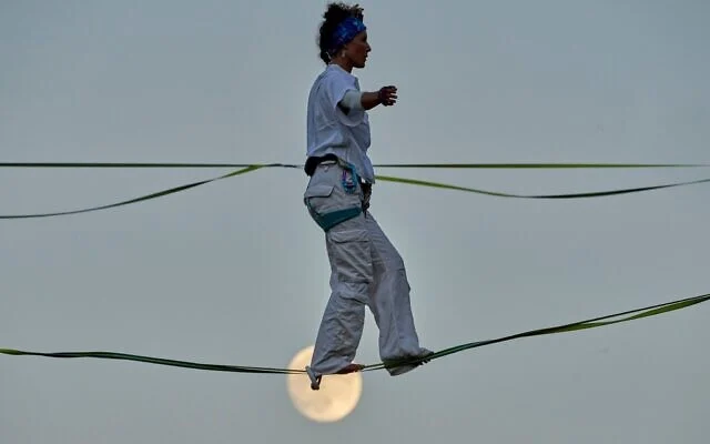 Une acrobate répète sur un fil tendu au-dessus de la vallée de Hinnom, à Jérusalem, avant sa performance aérienne à l'occasion de l'ouverture du Festival d'Israël, rappel de la traversée de cette vallée par Philippe Petit en 1987, le 27 juillet 2026. (AP Photo/Ohad Zwigenberg)