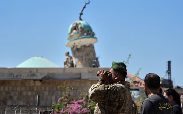 Un soldat libanais utilisant des jumelles pour observer le village de Zawtar al-Sharqiyah, contrôlé par l'armée israélienne, depuis Zawtar al-Gharbieh, dans le sud du Liban, le 28 juillet 2026. (Crédit : Hassan Ammar/AP)