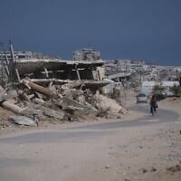 Un Gazaoui à vélo près des décombres de bâtiments détruits pendant la guerre entre Israël et le Hamas, dans le sud de la bande de Gaza, le 31 juillet 2026. (Crédit : Abdel Kareem Hana/AP)