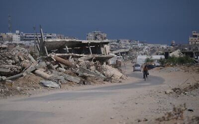 Un Gazaoui à vélo près des décombres de bâtiments détruits pendant la guerre entre Israël et le Hamas, dans le sud de la bande de Gaza, le 31 juillet 2026. (Crédit : Abdel Kareem Hana/AP)