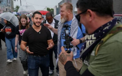 Abdul El-Sayed, candidat progressiste à la primaire démocrate pour le Sénat américain dans le Michigan, lors du tournage d'une vidéo pour les réseaux sociaux avec le créateur de contenu Russell Ellis en marchant de l'Anthology Coffee vers le Spirit of Detroit lors de la « March of the Many », le 2 août 2026 à Détroit. (Photo AP/Julia Demaree Nikhinson)