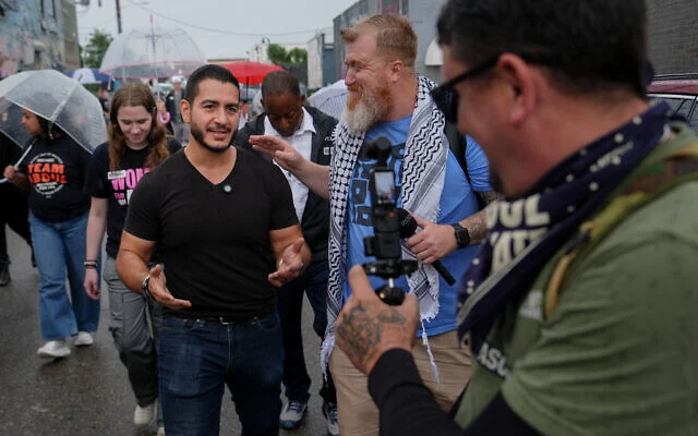 Abdul El-Sayed, candidat progressiste à la primaire démocrate pour le Sénat américain dans le Michigan, lors du tournage d'une vidéo pour les réseaux sociaux avec le créateur de contenu Russell Ellis en marchant de l'Anthology Coffee vers le Spirit of Detroit lors de la « March of the Many », le 2 août 2026 à Détroit. (Photo AP/Julia Demaree Nikhinson)