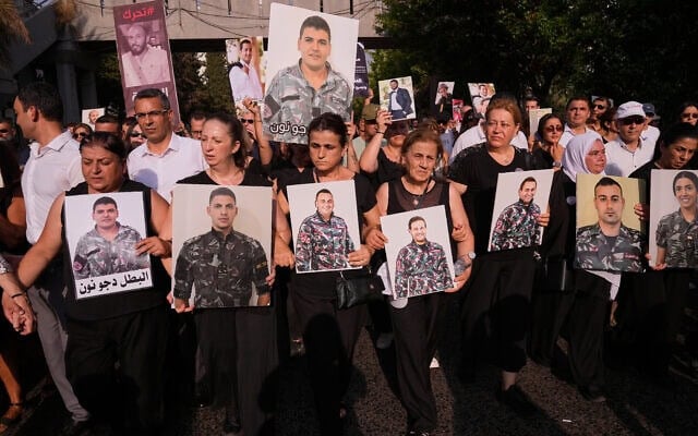 Les proches des pompiers tués lors de l'explosion du port de Beyrouth en 2020 brandissent leurs portraits, alors qu'ils défilent lors d'une cérémonie commémorative marquant le sixième anniversaire de cette gigantesque explosion à Beyrouth, au Liban, le mardi 4 août 2026. (Crédit : AP Photo/Hussein Malla)