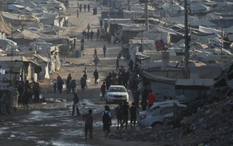 Des Palestiniens marchent parmi les tentes et les décombres sur la route côtière de Gaza-City, au nord de la bande de Gaza, le 13 août 2026. (Crédit : Abdel Kareem Hana/AP)
