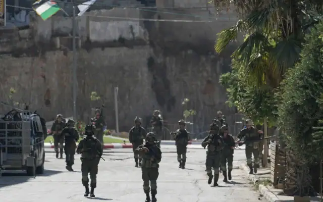 Des soldats de l'armée israélienne patrouillant dans les rues du village de Qusra, en Cisjordanie, au sud de Naplouse, le 13 août 2026. (Crédit : Majdi Mohammed/AP)