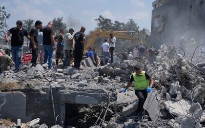 Des habitants et des secouristes rassemblés devant une maison détruite par une frappe aérienne israélienne, dans le village de Deir al-Zahrani, au sud du Liban, le 15 août 2026. (Crédit : Mohammed Zaatari/AP)