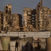 Des Palestiniens passent à proximité de tentes abritant des civils déplacés dans Gaza-City, le 17 août 2026. (AP Photo/Jehad Alshrafi)