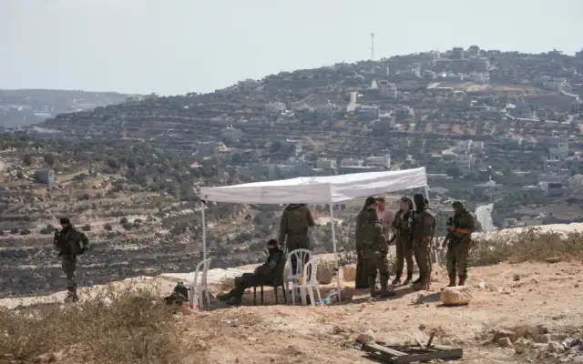 Des soldats israéliens devant la maison du Palestino-Américain Loui Abu Ridi, encerclée par des habitants des implantations, à Qusra, au sud de Naplouse, en Cisjordanie, le 19 août 2026. (Crédit : Majdi Mohammed/AP)