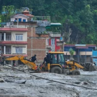 Les secouristes utilisant des engins de terrassement pour accéder aux maisons inondées à la suite d'une crue soudaine le long de la rivière Trishuli, dans le district de Nuwakot au Népal, le 26 août 2026. (Crédit : Niranjan Shrestha/AP)