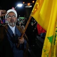 Un religieux iranien scandant un slogan et brandissant un drapeau du Hezbollah lors d'un rassemblement pro-régime, à Téhéran, le 26 août 2026. (Crédit : Vahid Salemi/AP Photo)