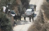 Des soldats de l’armée israélienne sécurisant un bâtiment en construction tandis que des ambulances évacuent des Palestiniens blessés à la suite d’une attaque perpétrée par des partisans du mouvement pro-implantations, dans le village de Qusra, en Cisjordanie, le 29 août 2026. (Crédit : Majdi Mohammed/AP)