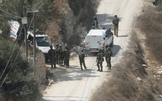 Des soldats de l’armée israélienne sécurisant un bâtiment en construction tandis que des ambulances évacuent des Palestiniens blessés à la suite d’une attaque perpétrée par des partisans du mouvement pro-implantations, dans le village de Qusra, en Cisjordanie, le 29 août 2026. (Crédit : Majdi Mohammed/AP)