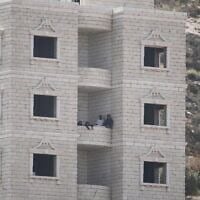 Des résidents d'implantation à l’intérieur d’un bâtiment palestinien en construction dans le village de Qusra, en Cisjordanie, le 29 août 2026. (Crédit : Majdi Mohammed/AP)