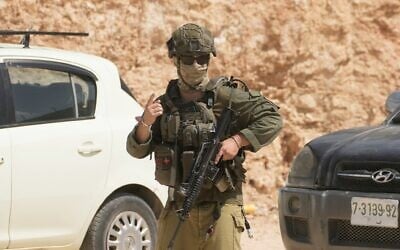 Un soldat de l'armée israélienne patrouillant sur les lieux d'une attaque perpétrée par des résidents d'implantation contre des biens palestiniens dans le village de Qusra, en Cisjordanie, le 29 août 2026. (Crédit : Majdi Mohammed/AP Photo) Un soldat de l'armée israélienne patrouillant sur les lieux d'une attaque perpétrée par des résidents d'implantation contre des biens palestiniens dans le village de Qusra, en Cisjordanie, le 29 août 2026. (Crédit : Majdi Mohammed/AP Photo)