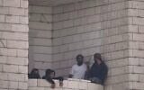 Des résidents d'implantation ayant attaqué un village palestinien sur le balcon d'un immeuble en construction, à Qusra, en Cisjordanie, le 29 août 2026. (Crédit : Majdi Mohammed/AP)