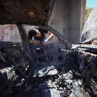 Illustration : Un Palestinien inspectant sa voiture calcinée après qu'elle a été incendiée par des résidents d'implantations, près de Bethléem, en Cisjordanie, le 29 juillet 2026. (Crédit : Wisam Hashlamoun/FLASH90)
