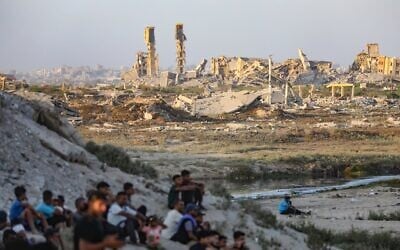 Des Palestiniens près de bâtiments détruits lors de la récente guerre entre Israël et le Hamas, à Gaza-City, au centre de la bande de Gaza, le 31 juillet 2026. (Crédit : Ali Hassan/Flash90)