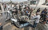 Des Gazaouis rassemblés sur les lieux d'une frappe israélienne visant un véhicule dans la rue Salah al-Din, à Deir al-Balah, au centre de la bande de Gaza, le 2 août 2026. (Crédit : Ali Hassan/Flash90)