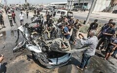 Des Gazaouis rassemblés sur les lieux d'une frappe israélienne visant un véhicule dans la rue Salah al-Din, à Deir al-Balah, au centre de la bande de Gaza, le 2 août 2026. (Crédit : Ali Hassan/Flash90)