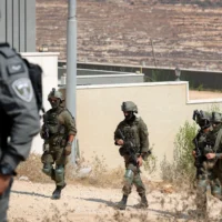 Des soldats devant des habitations ayant été assiégées par des résidents d'implantations, dans le village de Qusra, en Cisjordanie, le 14 août 2026. (Crédit : Flash90)