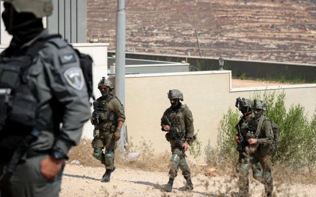 Des soldats devant des habitations ayant été assiégées par des résidents d'implantations, dans le village de Qusra, en Cisjordanie, le 14 août 2026. (Crédit : Flash90)