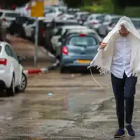 Un homme marchant sous la pluie, à Jérusalem, le 15 août 2026. (Crédit : Yossi Zamir/Flash90)