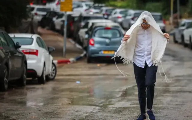 Un homme marchant sous la pluie, à Jérusalem, le 15 août 2026. (Crédit : Yossi Zamir/Flash90)