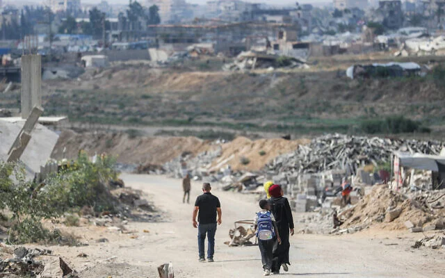 Photo d'illustration: Des Gazaouis marchant au milieu des décombres issus de la guerre, dans la ville d'al-Zahra, dans le centre de la bande de Gaza, le 22 août 2026. (Crédit : Ali Hassan/Flash90)