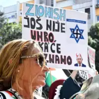 Une femme frappe sur une casserole à côté d'une pancarte disant « Le sionisme n'est pas encore mort, et nous ne savons pas quand il le sera », lors d'un rassemblement pro-palestinien et anti-Israël à Podgorica, au Monténégro, le 14 septembre 2025. (Photo de SAVO PRELEVIC / AFP)